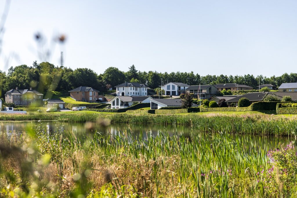 Et boligkvarter med villaer i baggrunden og en sø i forgrunden