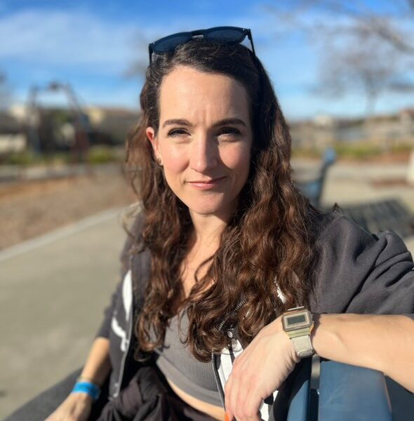 Jessica sidder på en bænk og kigger direkte på dig
