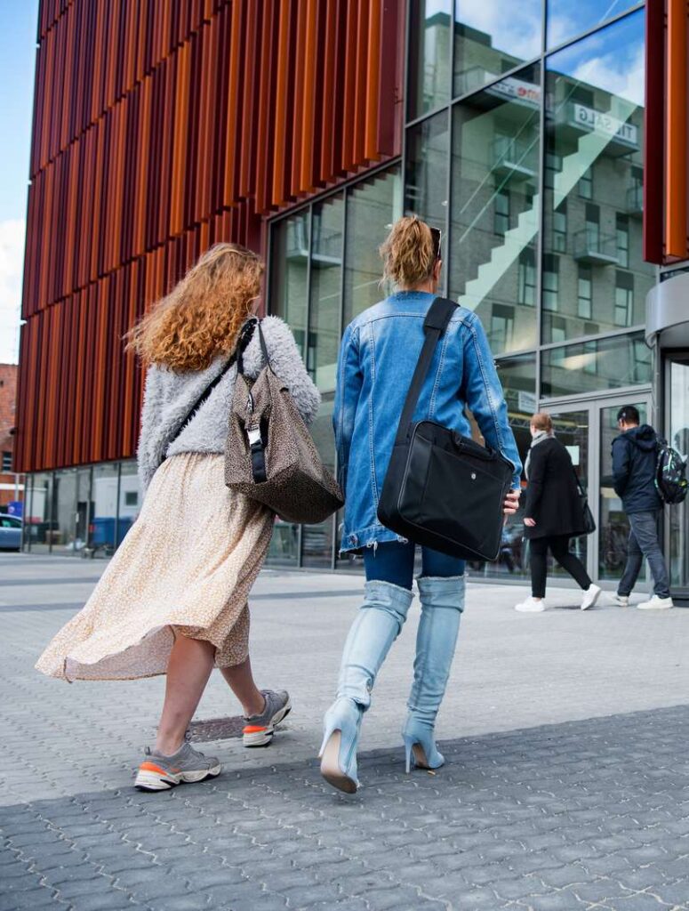 Two students are walking towards a red building (IBA)